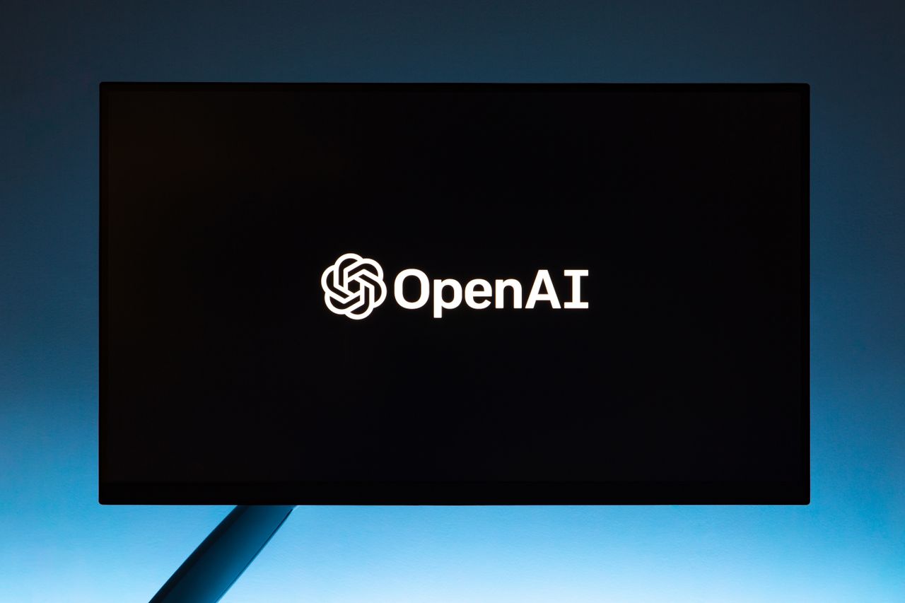 services-03 Minimalist display of OpenAI logo on a screen, set against a gradient blue background.